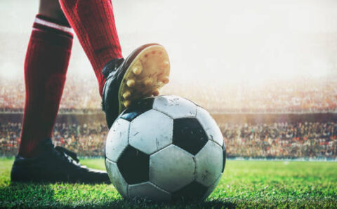 feet of soccer player tread on soccer ball for kick-off in the stadium